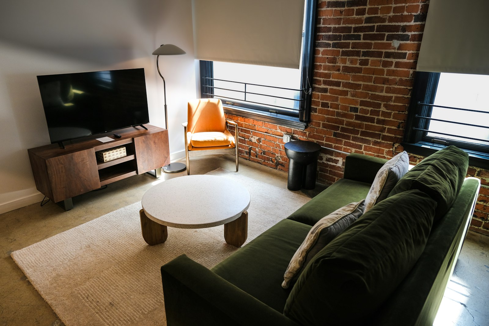 Illustrative photo of a boutique-style living space with a green velvet sofa, exposed brick and tall windows, not taken at a hotel in this guide